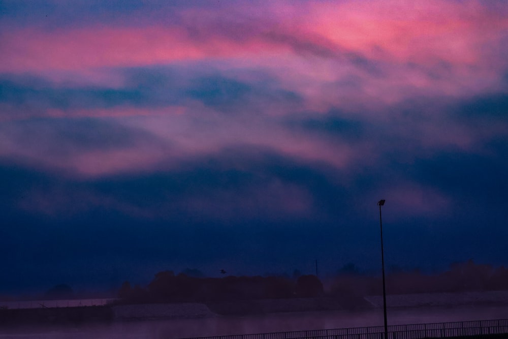 a red and blue sky with clouds and a street light