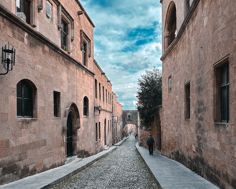 a man is walking down a cobblestone street