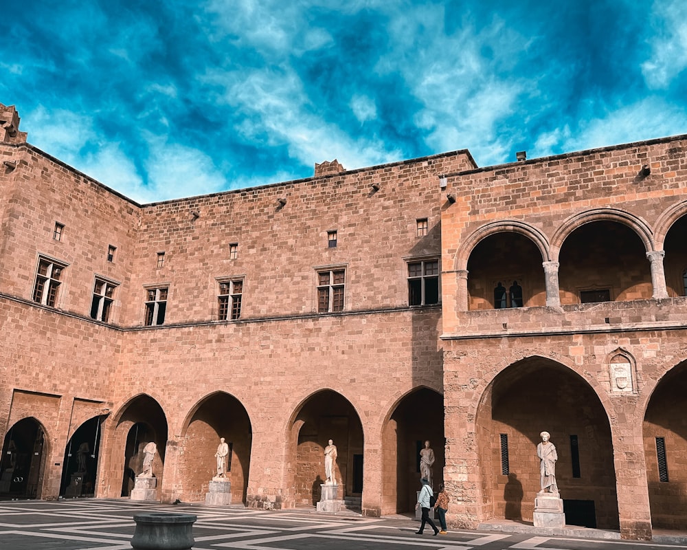 a courtyard with statues and arches under a blue sky