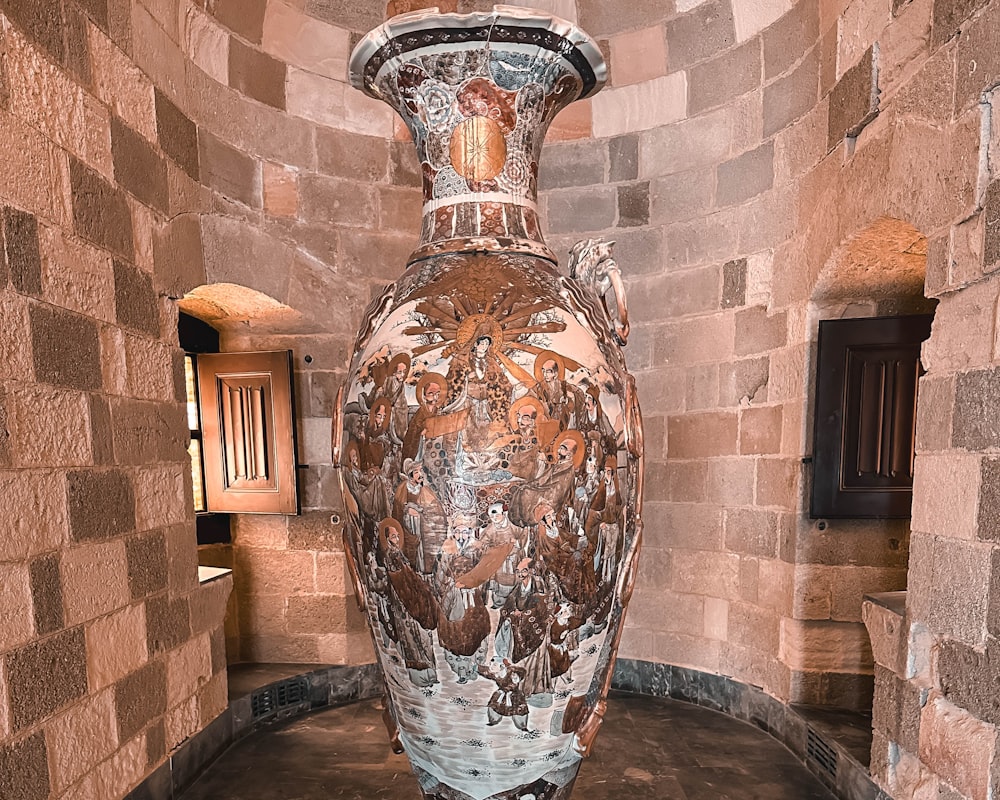 un grande vaso seduto in una stanza accanto a un muro di mattoni