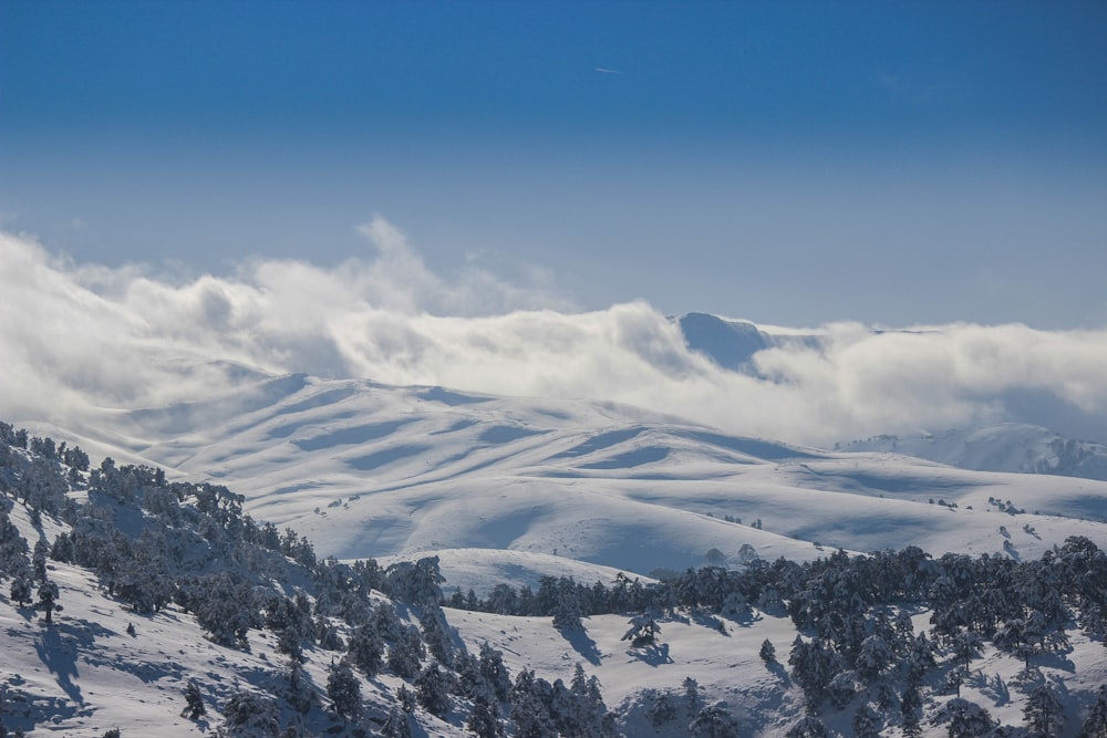 a view of a snowy mountain range with clouds in the sky