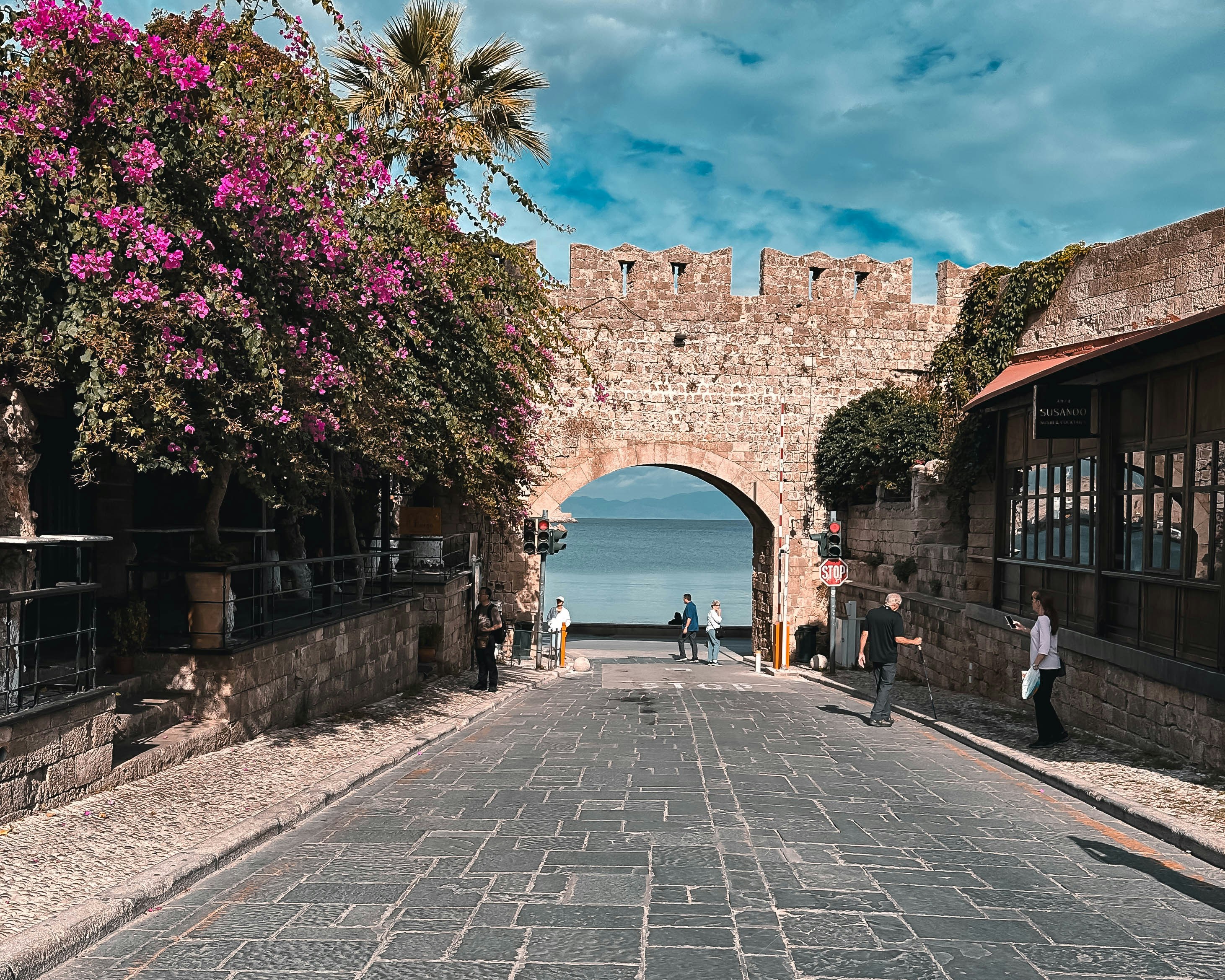 a cobblestone street with a stone arch leading to the ocean