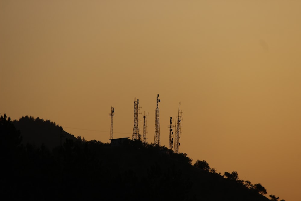 the sun is setting over a hill with cell towers