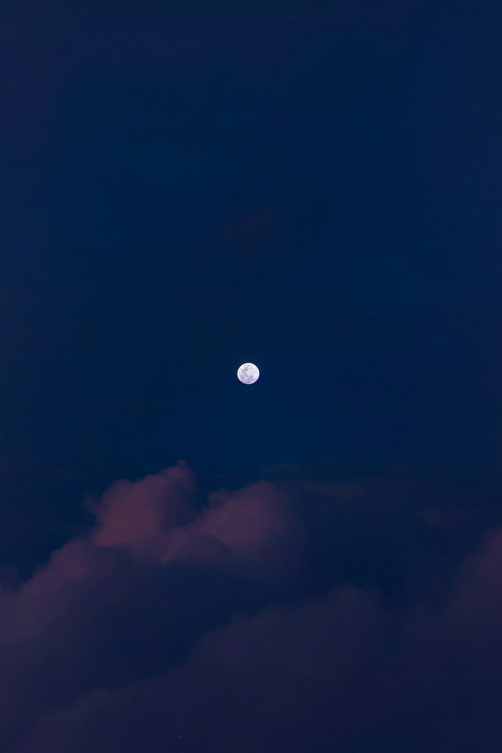 a full moon is seen through the clouds