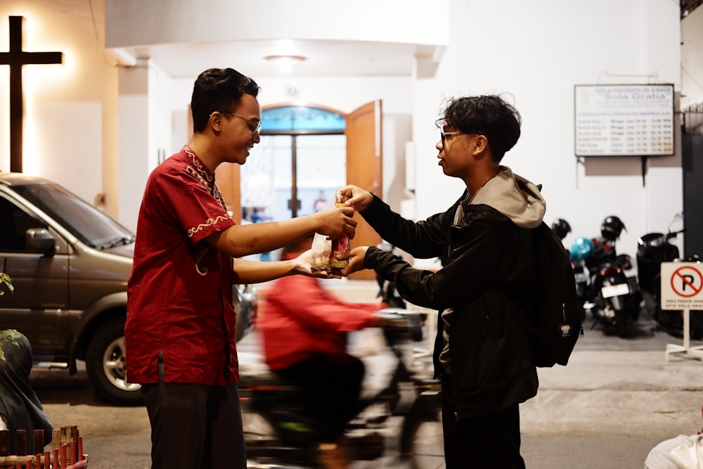 a man handing another man a bottle of beer