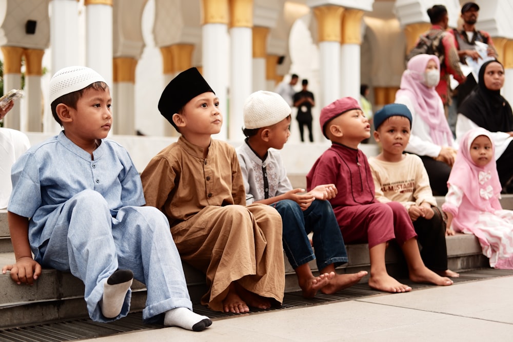 a group of children sitting on a step in front of a building