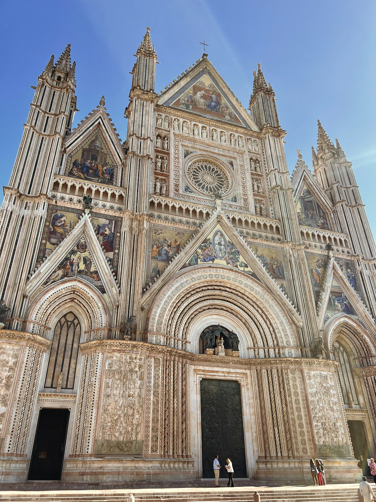 Orvieto's Gothic cathedral facade glowing gold at sunset above the Umbrian plain