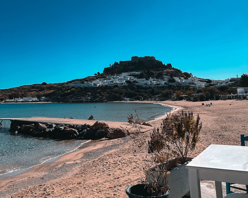 a table and chairs on a beach near the water