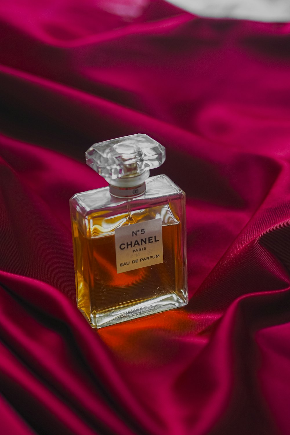 Un flacon de parfum Chanel posé sur un tissu rouge