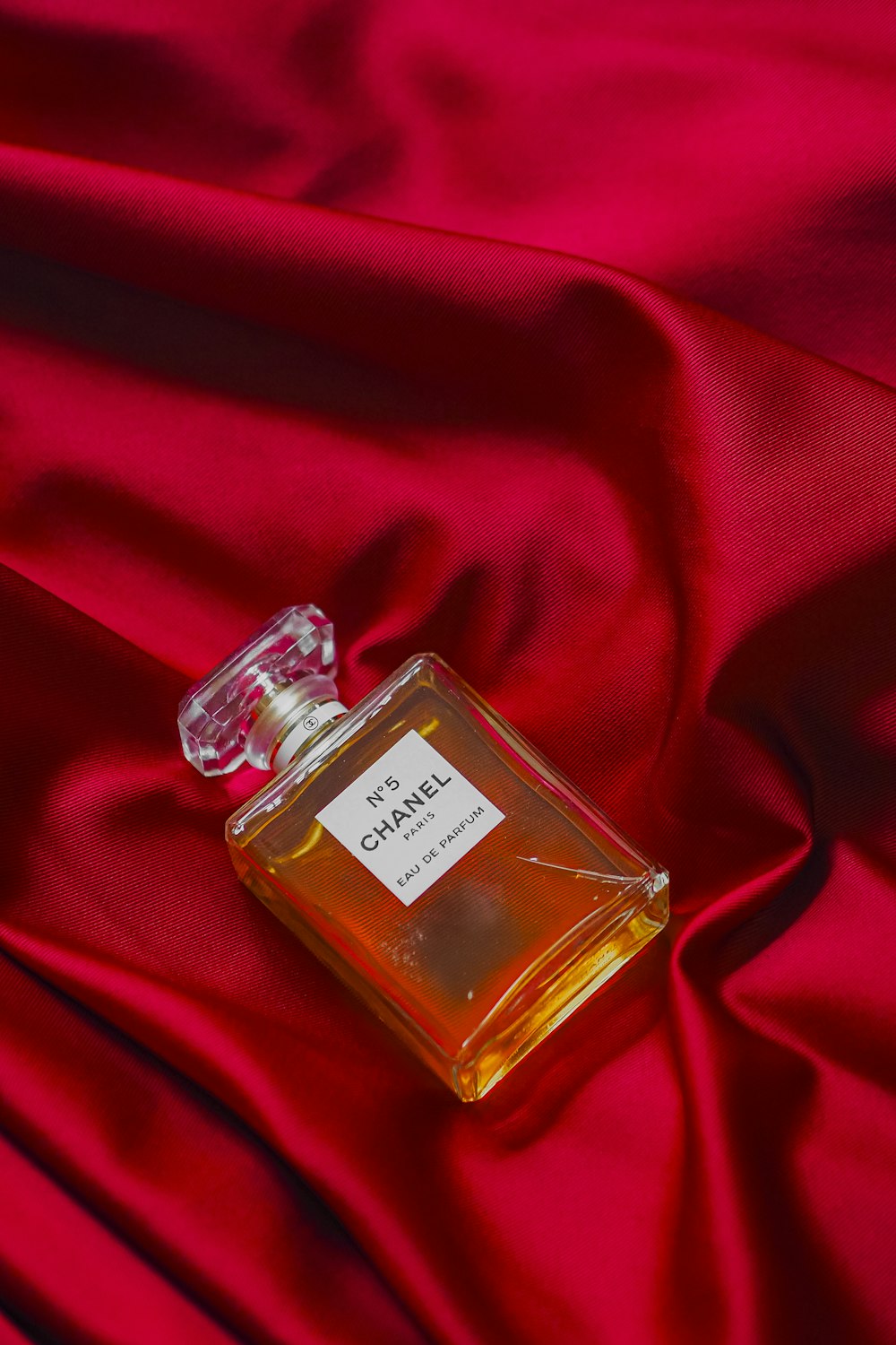 a bottle of perfume sitting on top of a red cloth