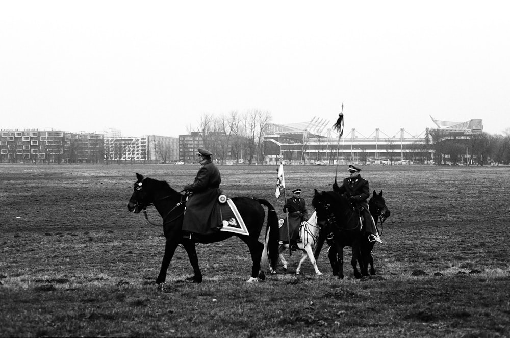 a black and white photo of a group of people on horses