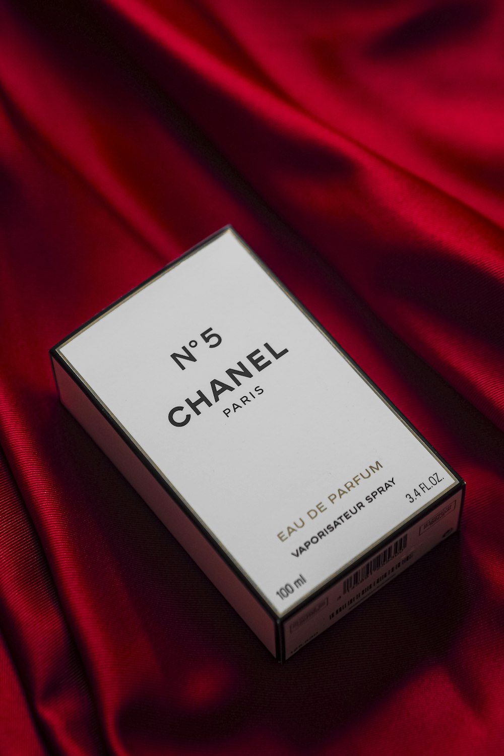 une boîte de Chanel n°5 sur un tissu rouge