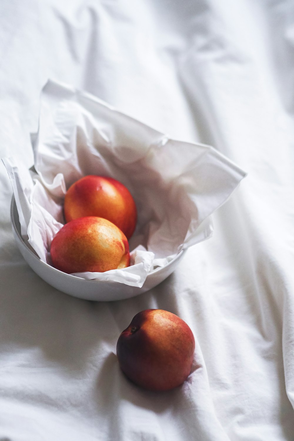 un bol de pommes posé sur un lit
