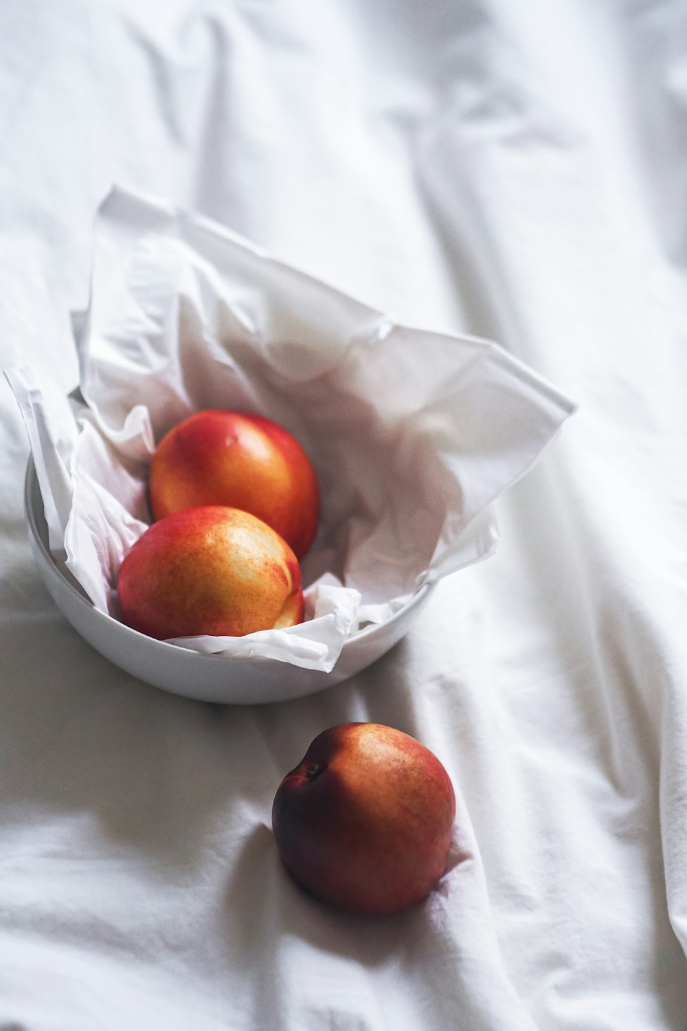 a bowl of apples sitting on top of a bed