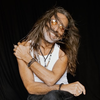 a man with long hair sitting on a chair