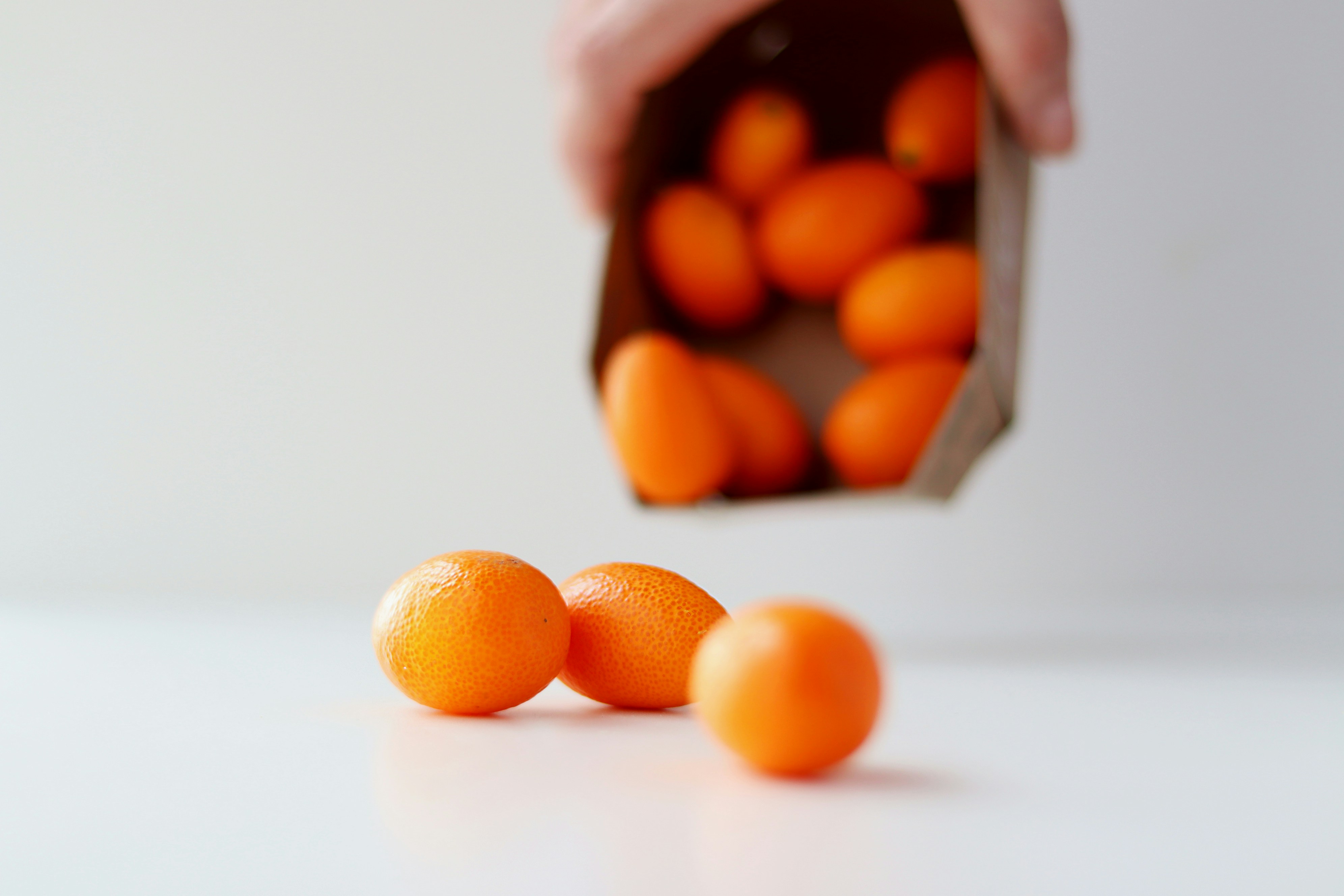 a person holding a paper bag full of oranges