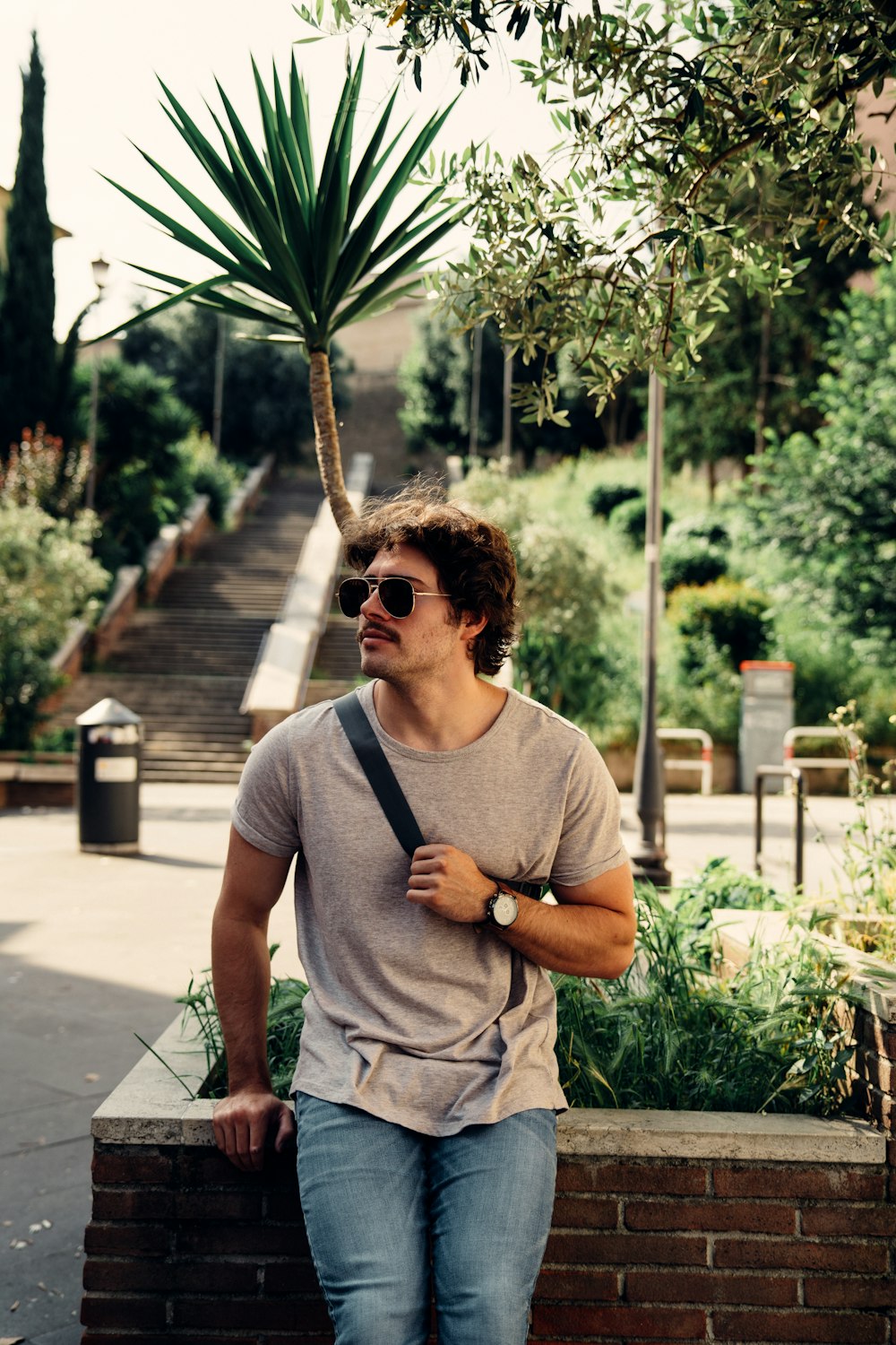 a man sitting on a brick wall next to a tree