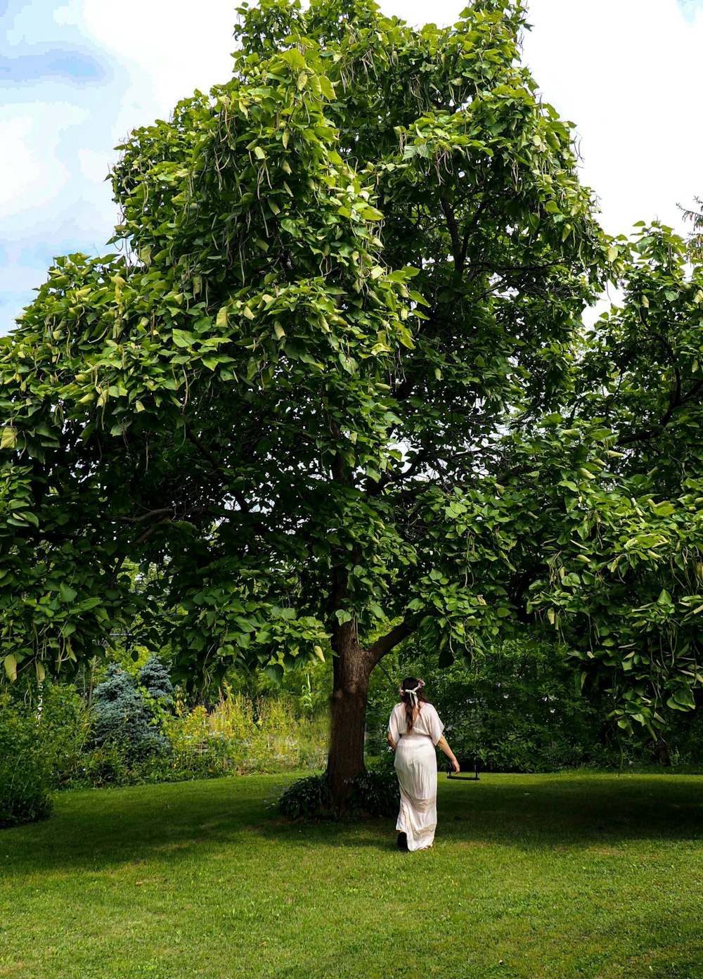 a woman in a white dress standing under a tree