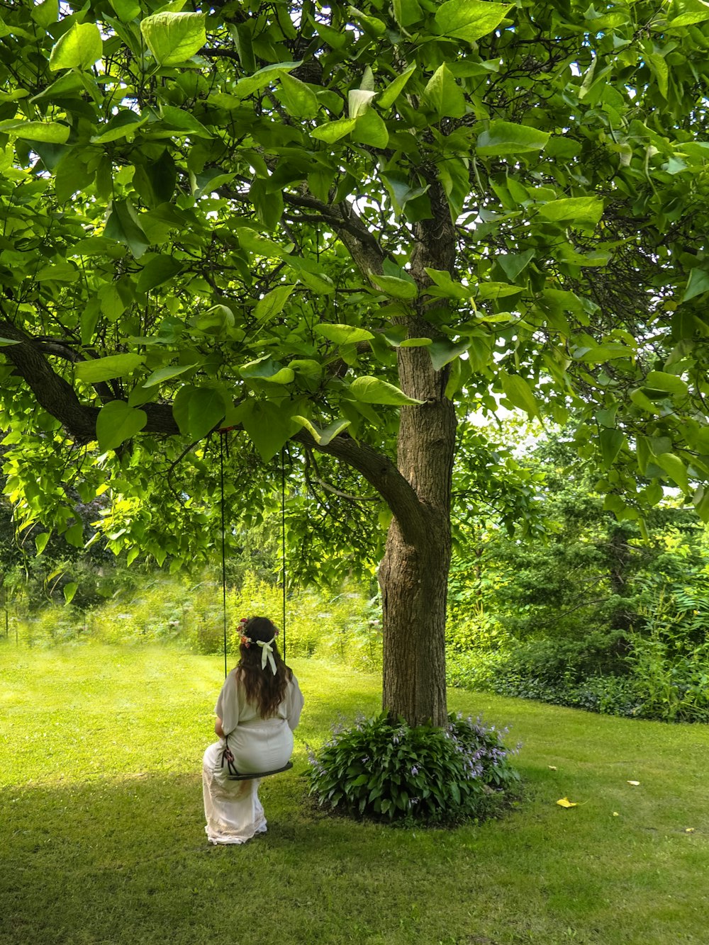 a woman sitting on a swing under a tree