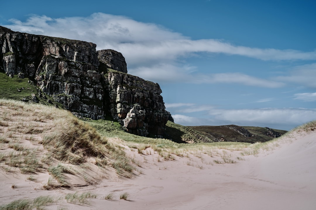 a sandy path leading to a large rock outcropping,