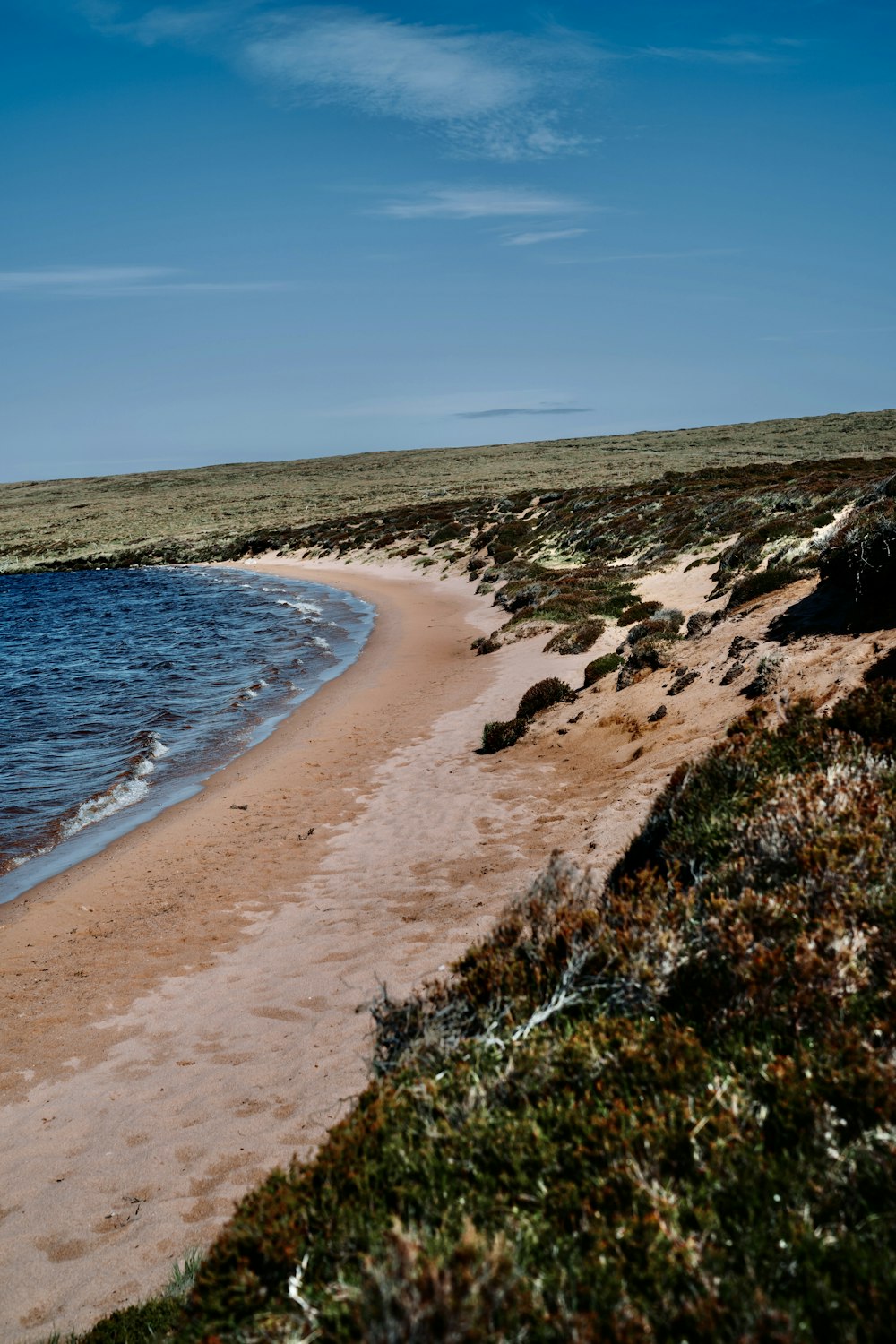 a sandy beach next to a body of water