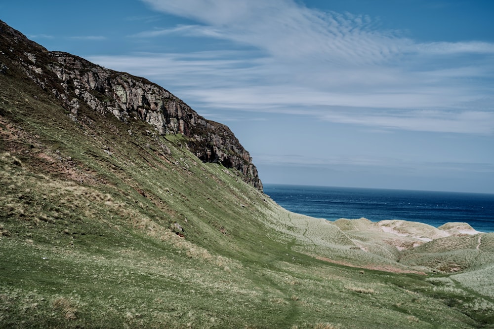 a grassy hill next to a body of water