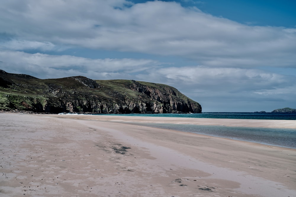 a sandy beach with a mountain in the background