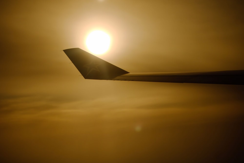 a plane wing with the sun in the background