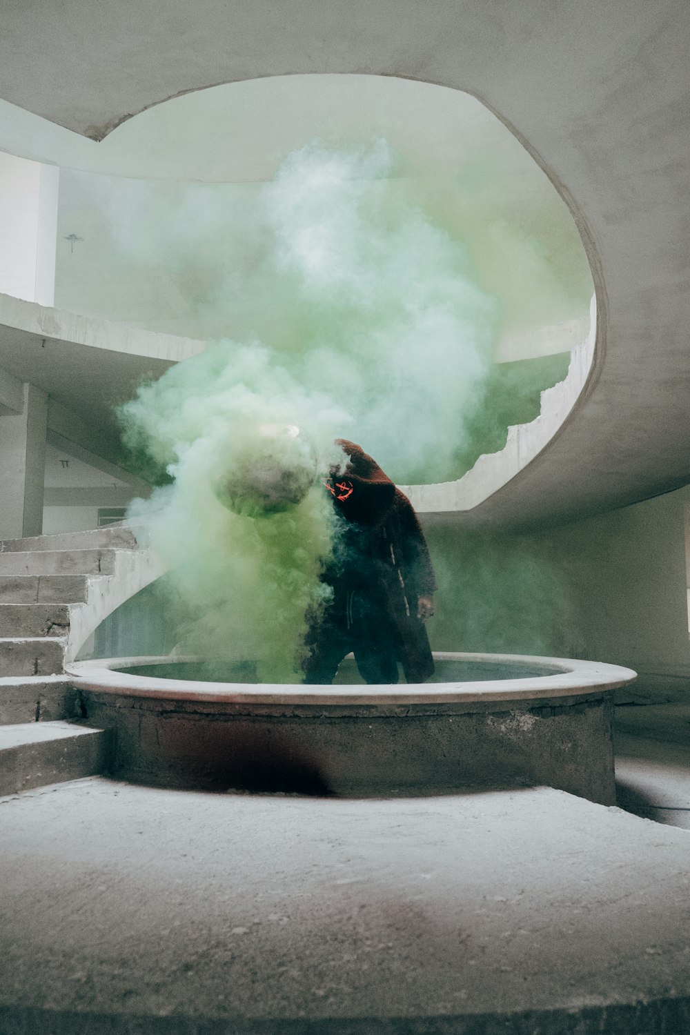a man standing in front of a fountain filled with green smoke