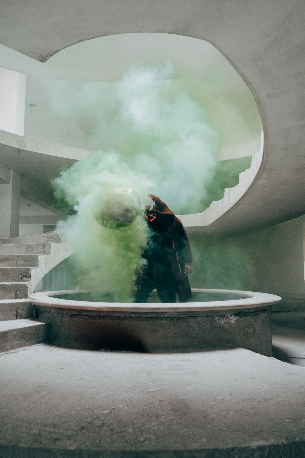 un uomo in piedi davanti a una fontana piena di fumo verde