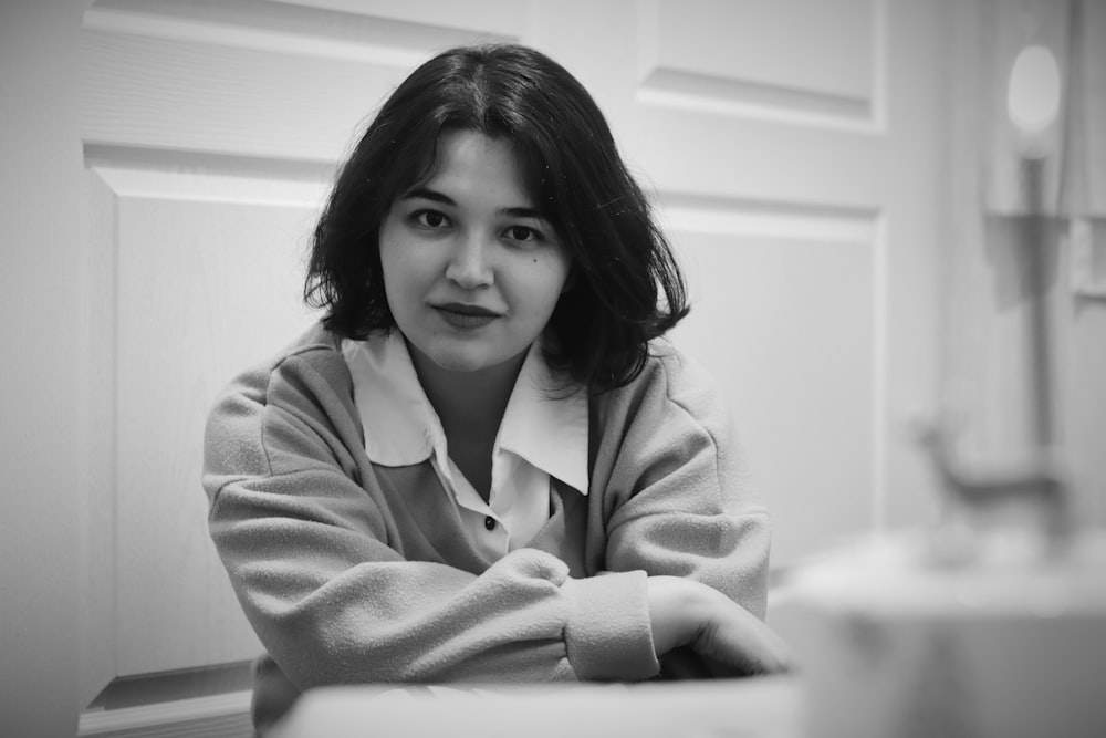 a black and white photo of a woman sitting at a table