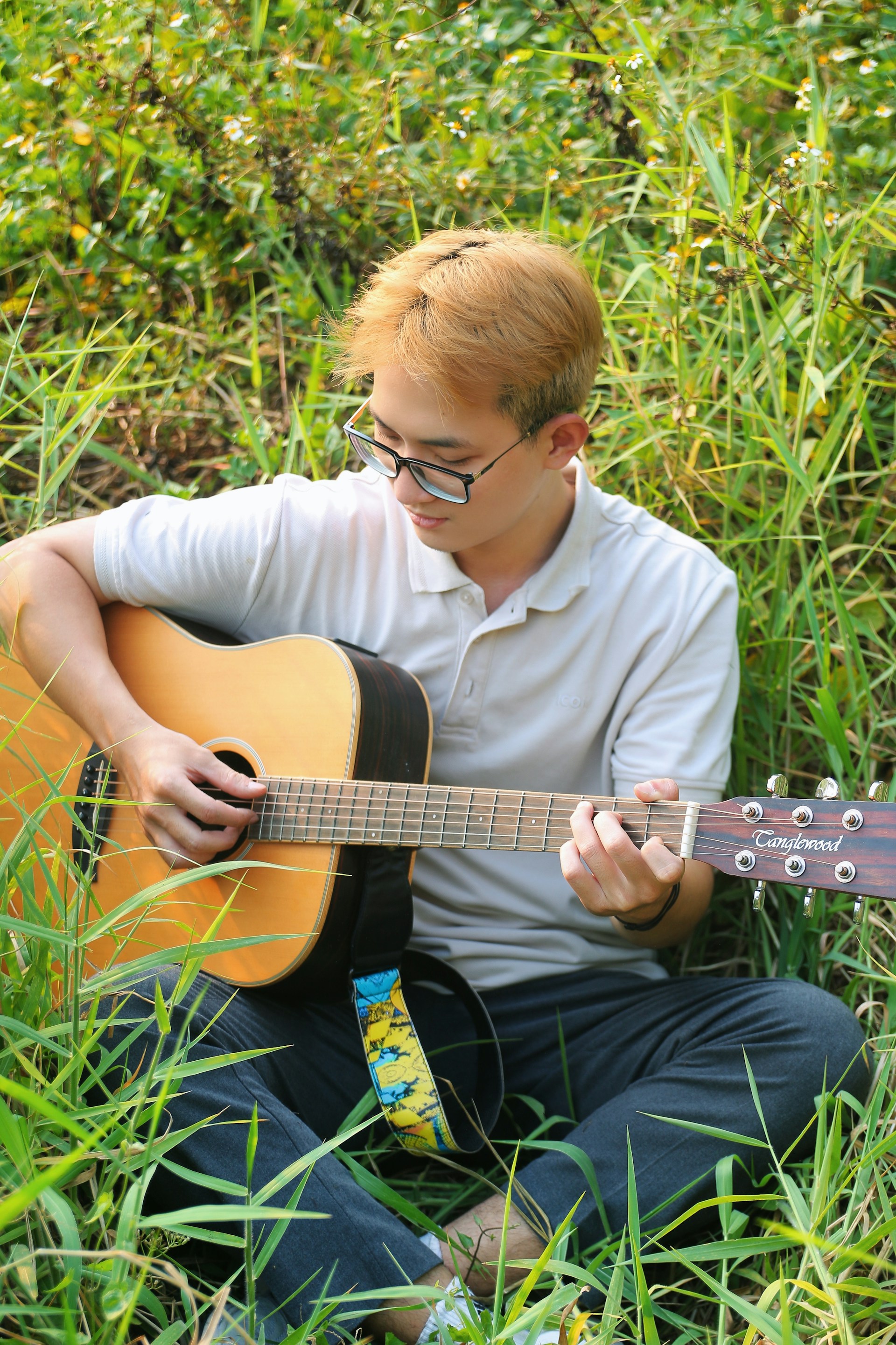 a man sitting in the grass playing a guitar