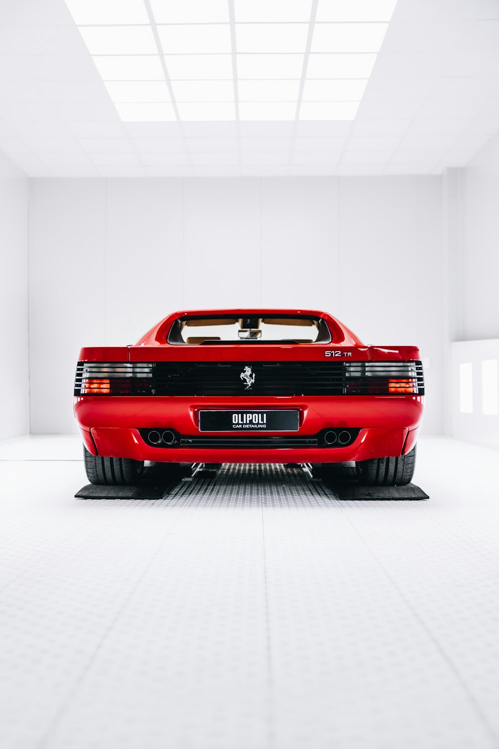 Un coche deportivo rojo aparcado en una habitación blanca
