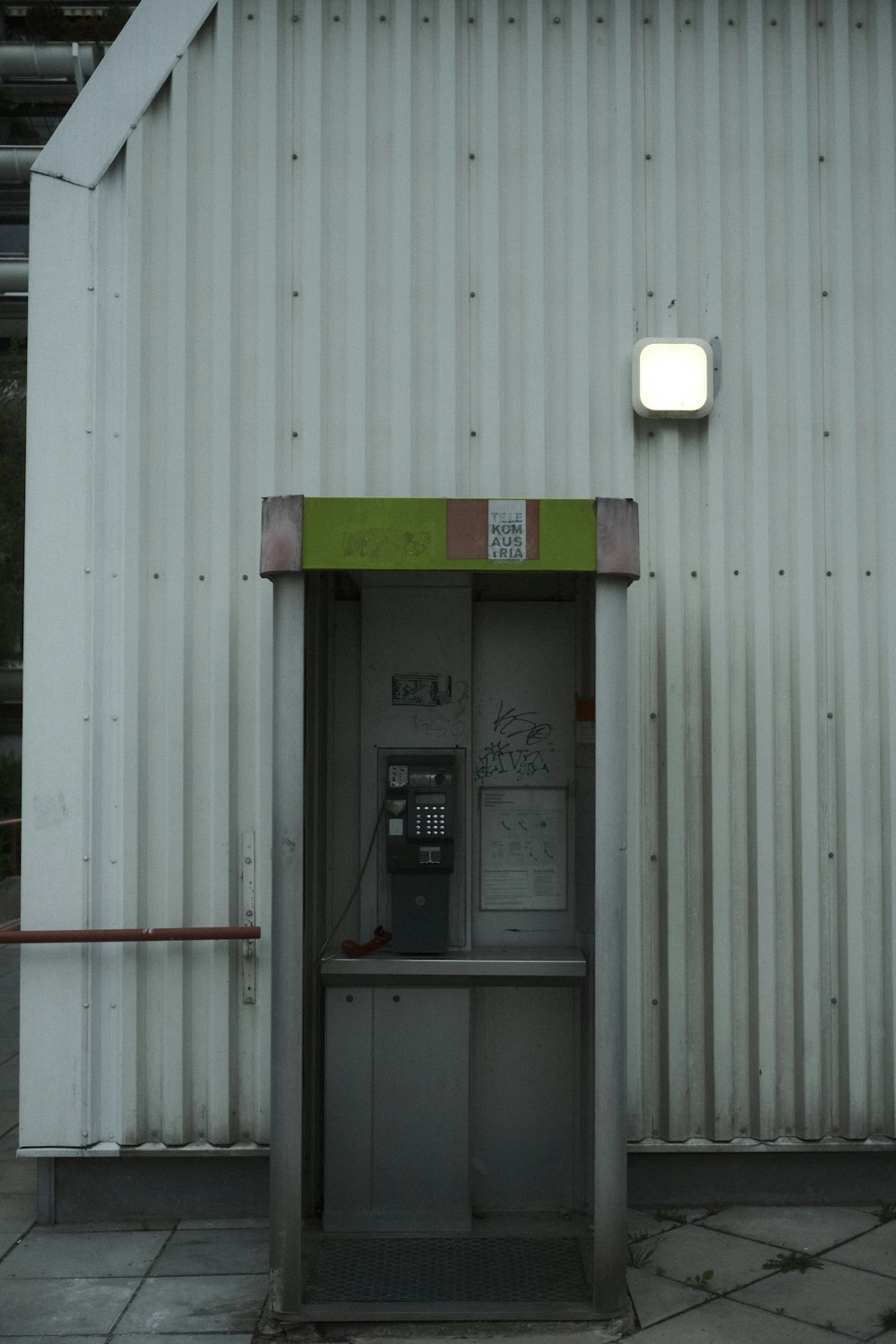a white building with a green door and a phone