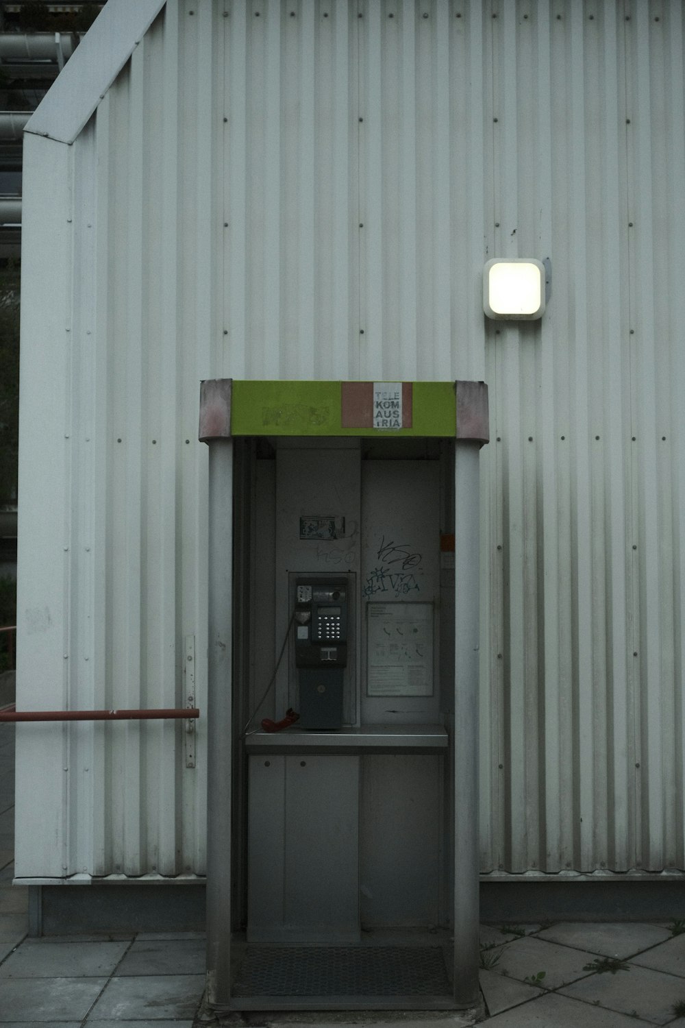 Un edificio bianco con una porta verde e un telefono