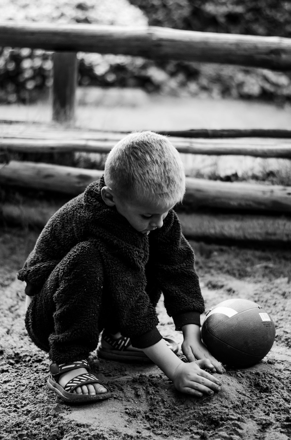 a little boy playing with a ball in the sand
