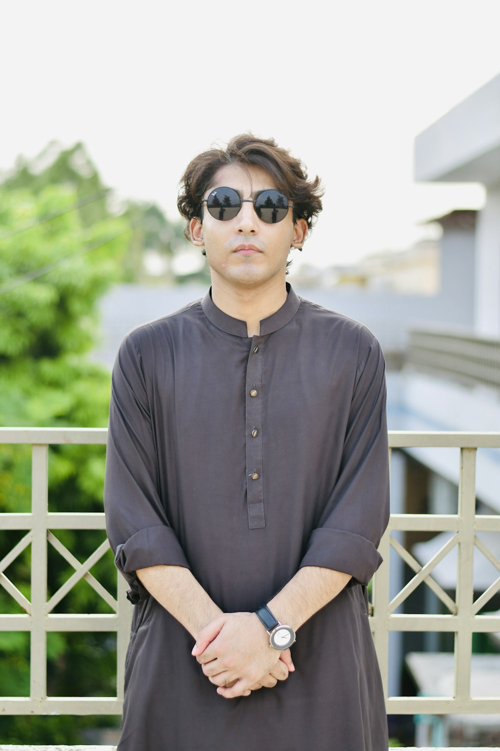 a man wearing sunglasses standing in front of a fence