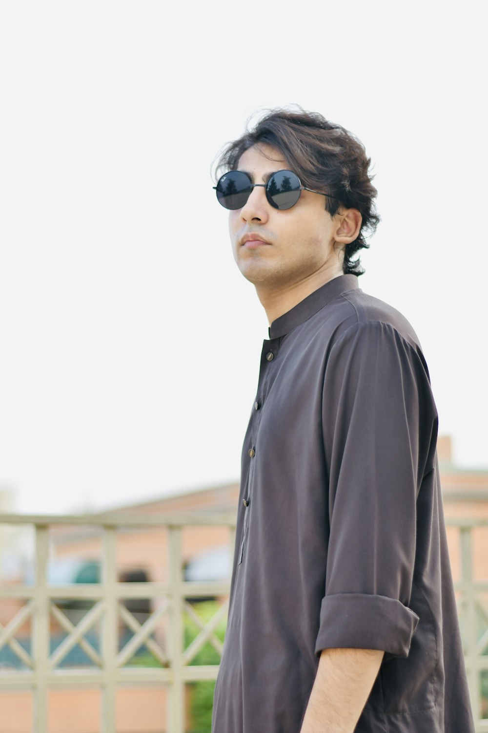 a man with sunglasses standing in front of a fence