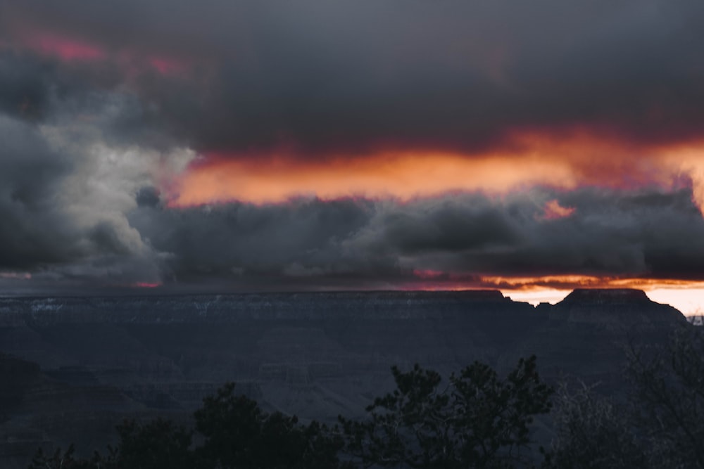 the sun is setting over the mountains and clouds