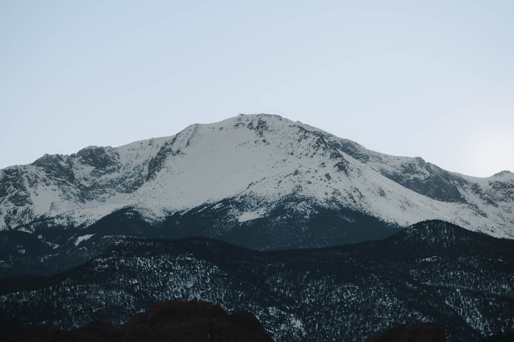 a snow covered mountain with trees in the foreground