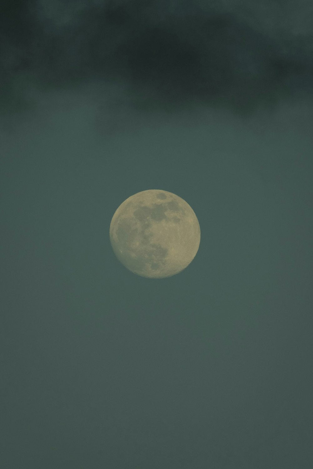 a full moon is seen through the dark clouds