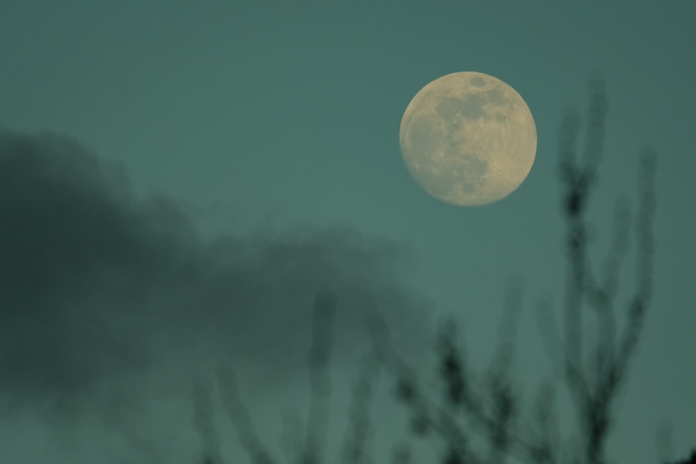 a full moon is seen through the clouds