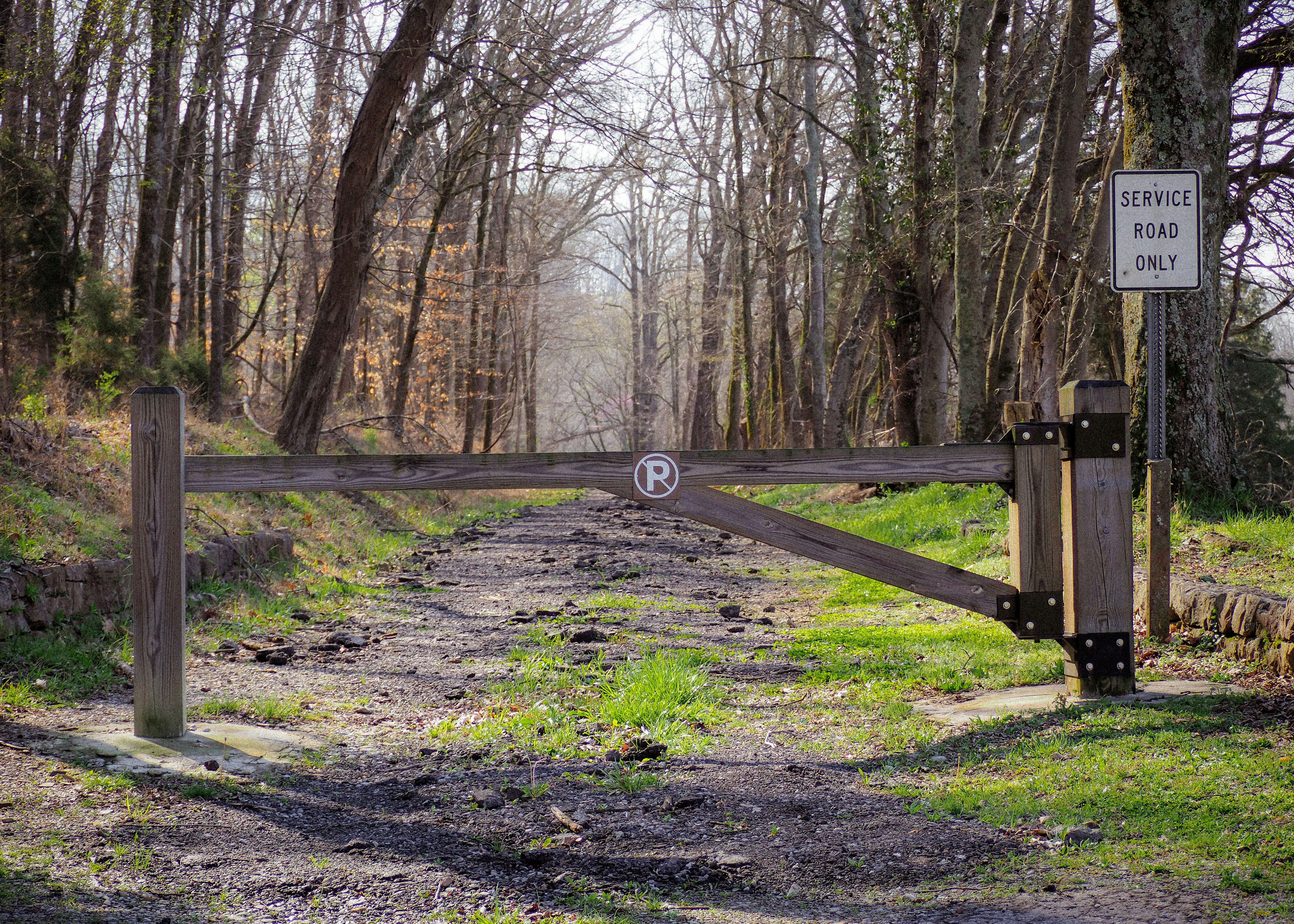 a wooden gate in the middle of a dirt road