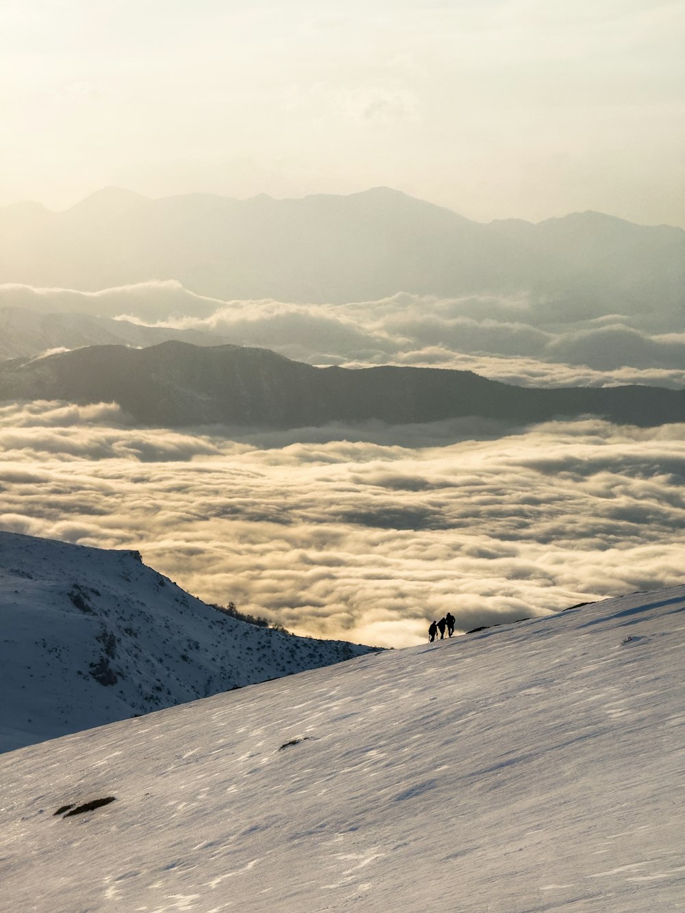 a couple of people riding skis on top of a snow covered slope