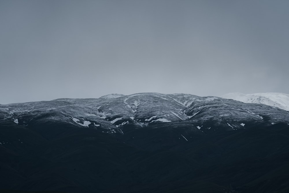 a mountain range covered in snow on a cloudy day