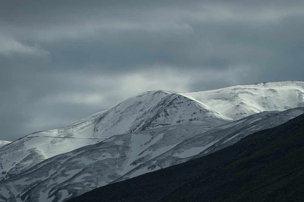 a mountain covered in snow under a cloudy sky