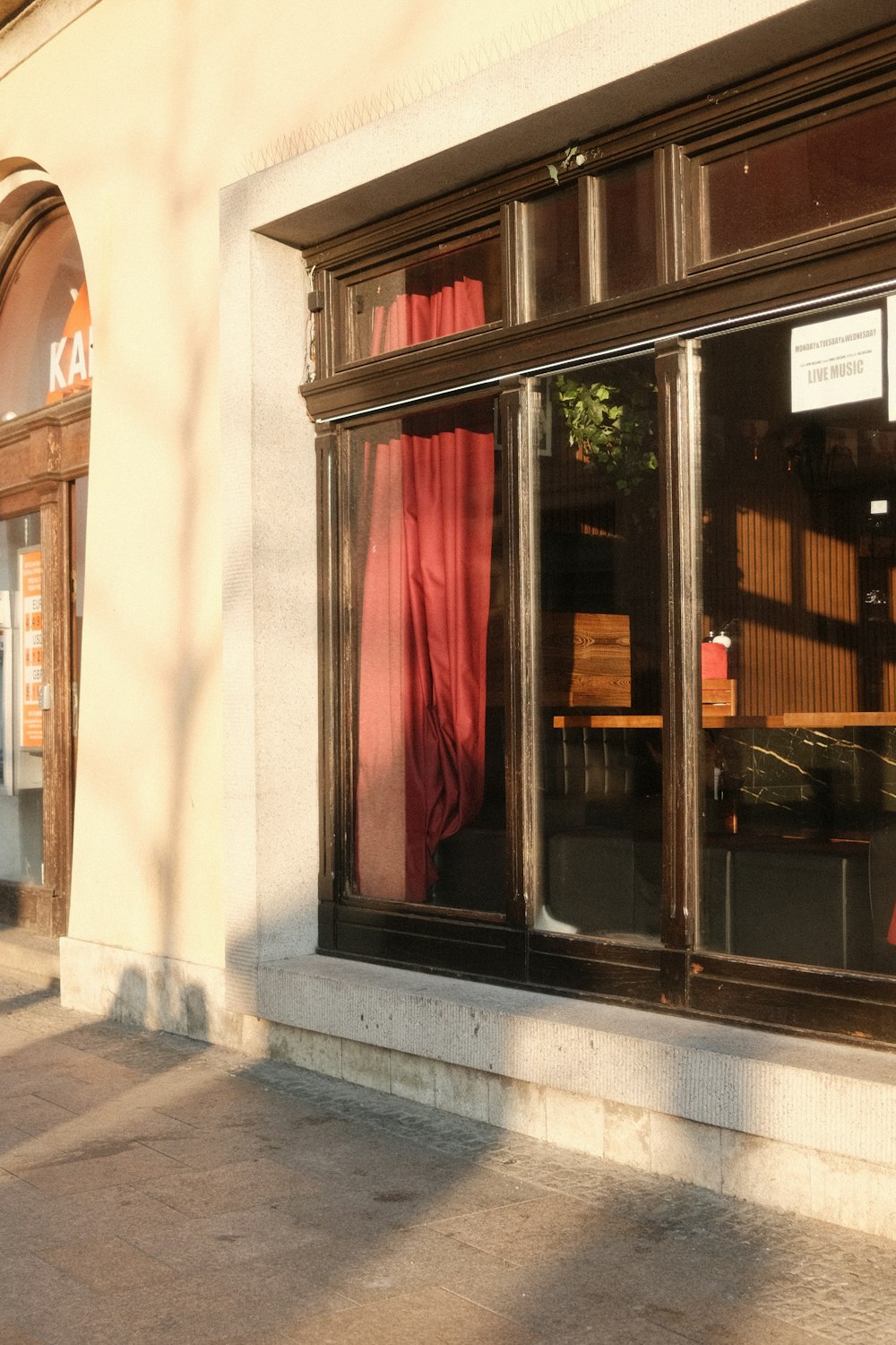 a store front with red curtains and a clock