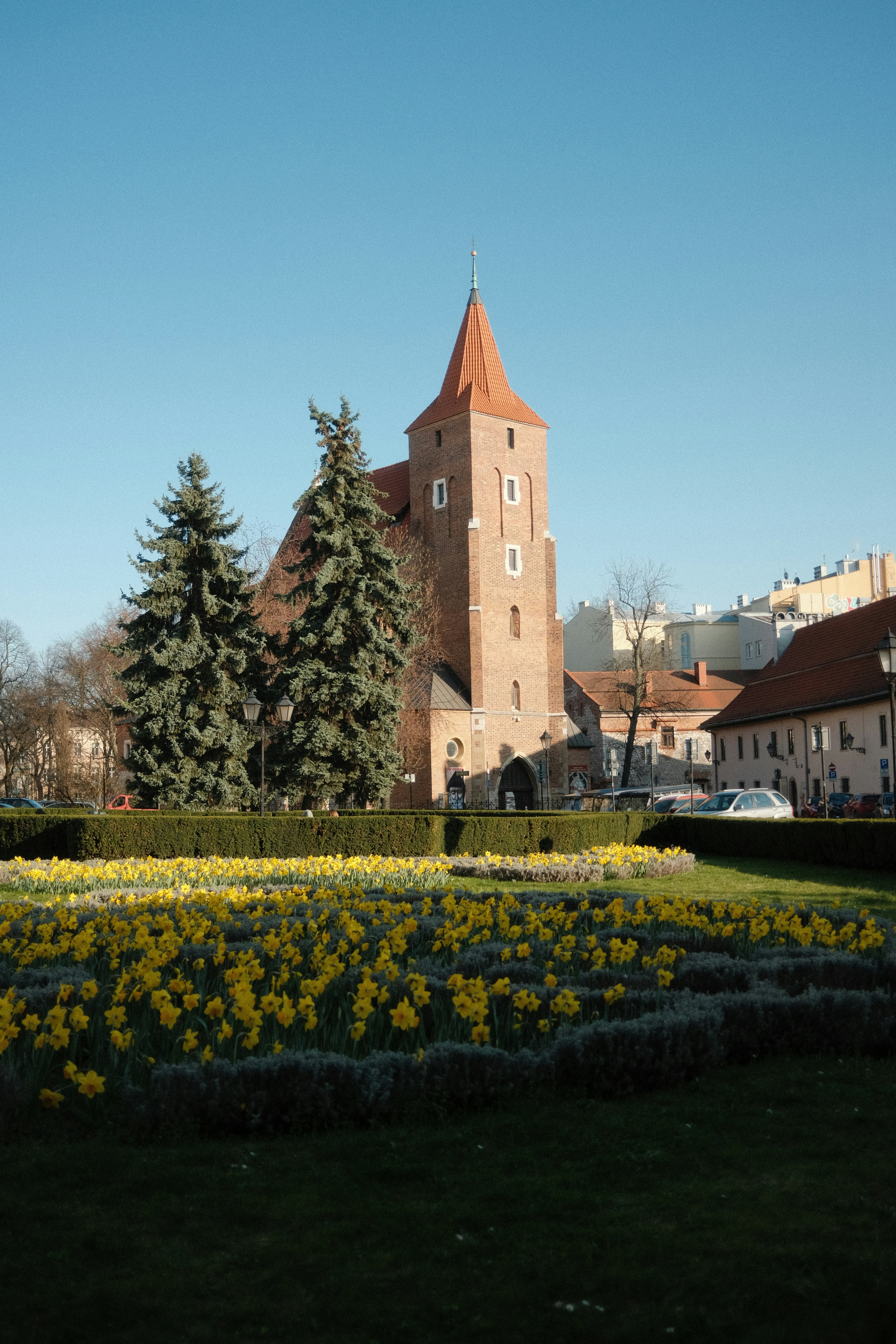 a large building with a clock tower in the middle of a field of flowers
