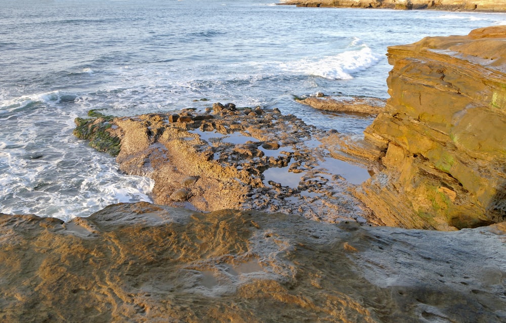 a rocky cliff with a body of water in the background