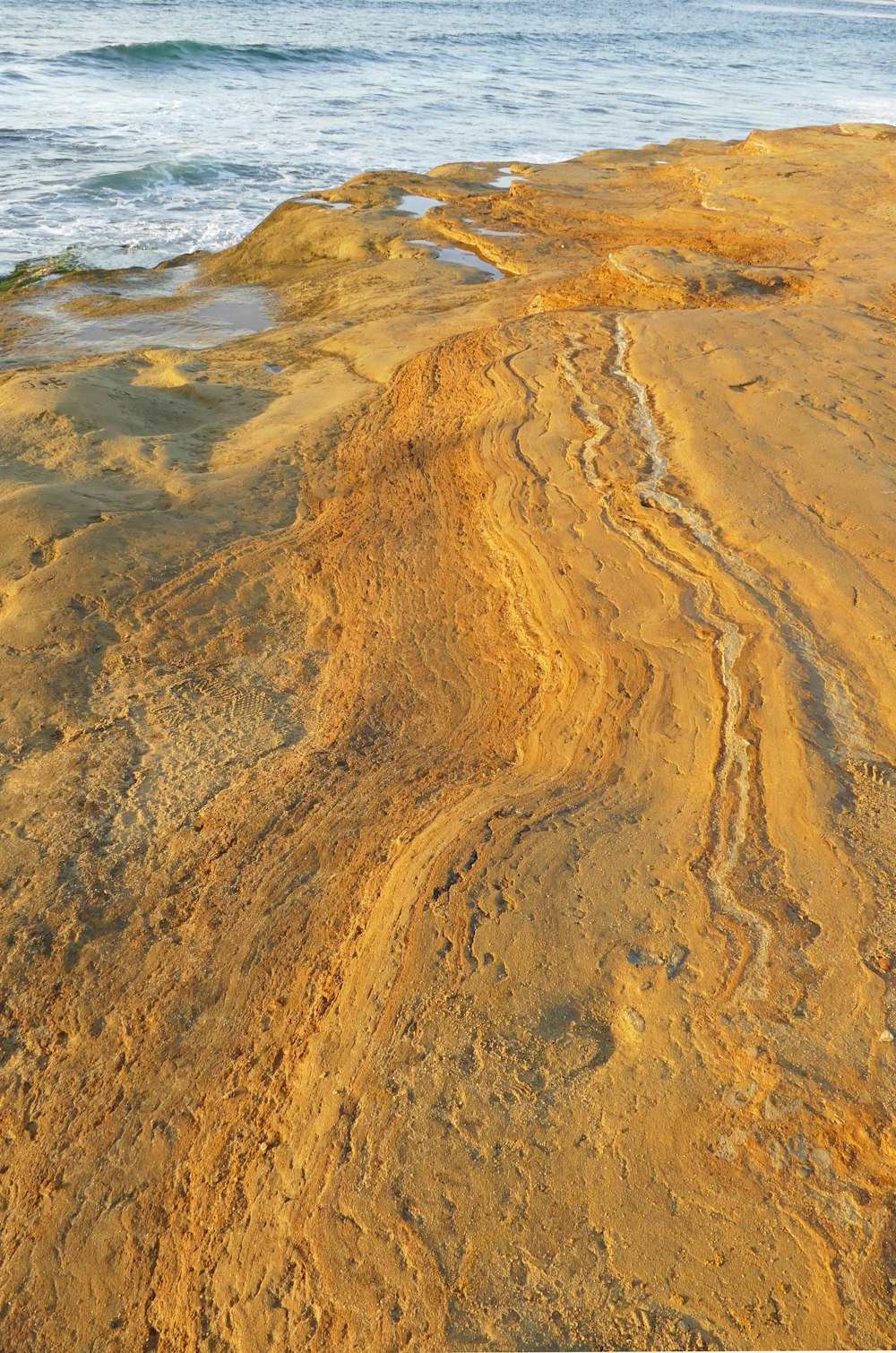 una playa de arena con un cuerpo de agua al fondo